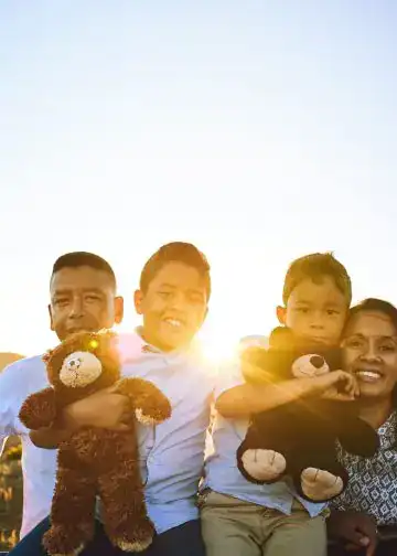 Familia multicultural disfrutando al atardecer, reflejando inmigración, integración y comunidad en la revista SoyMigrante.com REVISTA.