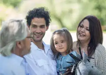 Familia multicultural disfrutando del tiempo en un parque, promoviendo la integración y el bienestar familiar en un entorno natural.