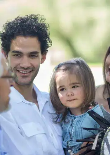 Familia multicultural disfrutando del tiempo en un parque, promoviendo la integración y el bienestar familiar en un entorno natural.