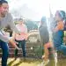 Diversión familiar en un jardín con niños jugando y adultos disfrutando del momento, promoviendo valores de migrantes y comunidad en SoyMigrante.com Revista.