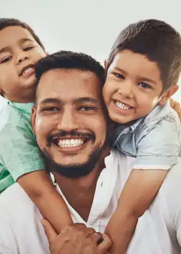 Diversos niños sonrientes abrazando a un adulto, reflejando felicidad, unión familiar y alegría, en una imagen que promueve valores de comunidad y bienestar.