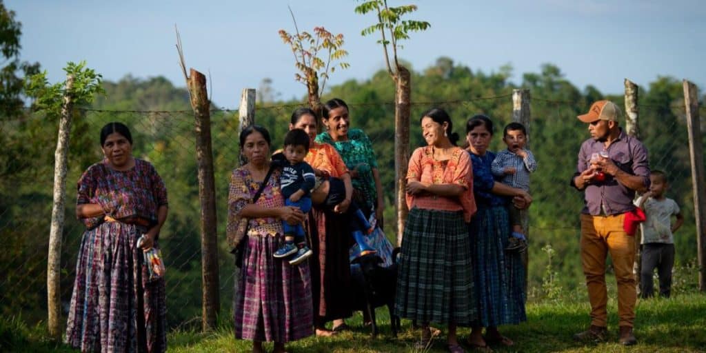 Diversas mujeres y niños migrantes en un entorno rural, evidenciando la vida y comunidad de inmigrantes en América Central y México. – SoyMigrante.com REVISTA