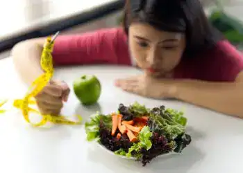 Imagen de mujer observando ensalada saludable con manzana y productos frescos, promoviendo vida sana, alimentación saludable y bienestar.