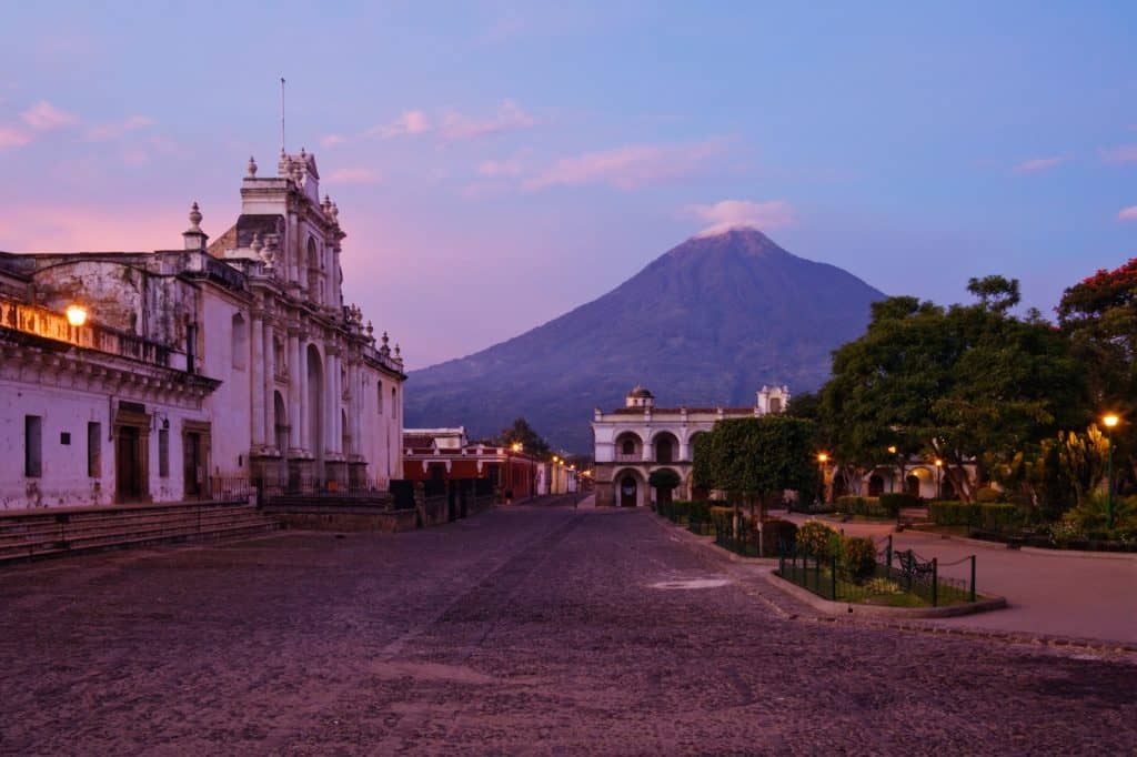 Catedral de Antigua Guatemala con volcán de Fuego al fondo al atardecer. Poblado histórico y volcánico en Guatemala, con arquitectura colonial y paisajes naturales impresionantes.