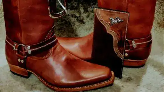 Botas de charro mexicanas de cuero marrón con espuelas y libro de fiesta tradicional.