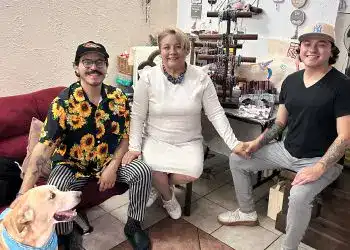 Cercano a una mujer y dos jóvenes en un ambiente acogedor, rodeados de artesanías y accesorios, promoviendo la cultura y el talento de migrantes en un espacio de comunidad y arte.