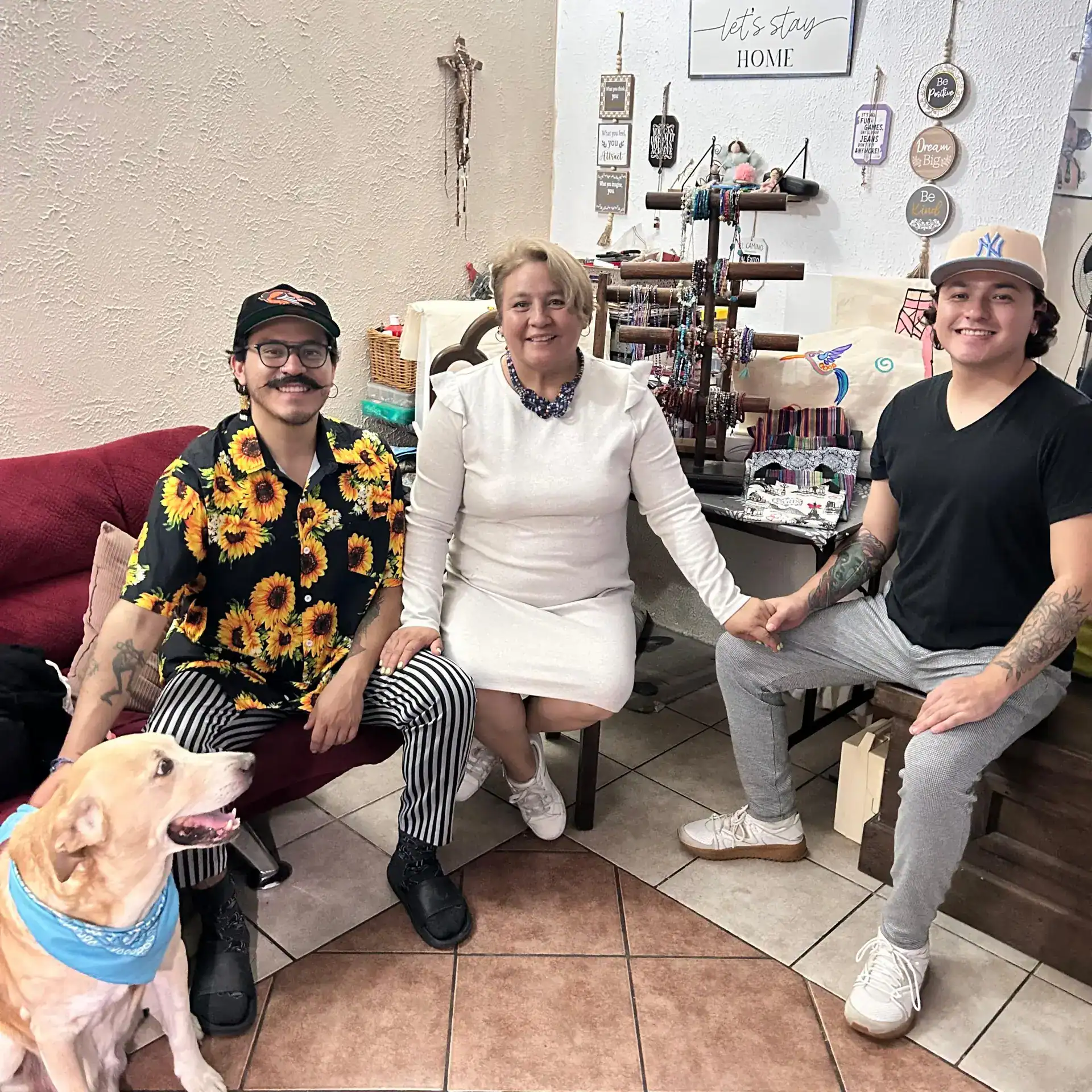 Cercano a una mujer y dos jóvenes en un ambiente acogedor, rodeados de artesanías y accesorios, promoviendo la cultura y el talento de migrantes en un espacio de comunidad y arte.