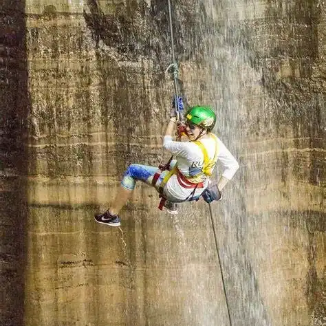 Persona haciendo rappel desde una pared de roca durante una aventura de deporte extremo en exterior.