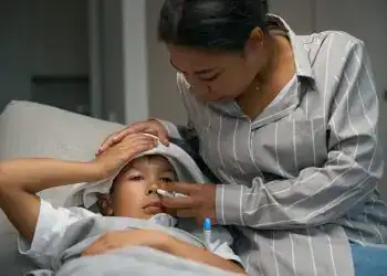 Enfermera atendiendo a un niño enfermo con fiebre en la clínica, atención médica infantil, cuidado y salud para migrantes y comunidades vulnerables.