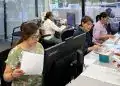 Trabajadoras migrantes en oficina, desempeñando tareas administrativas y revisando documentos en un entorno laboral dedicado a la comunidad migrante en la revista SoyMigrante.com. – SoyMigrante.com REVISTA
