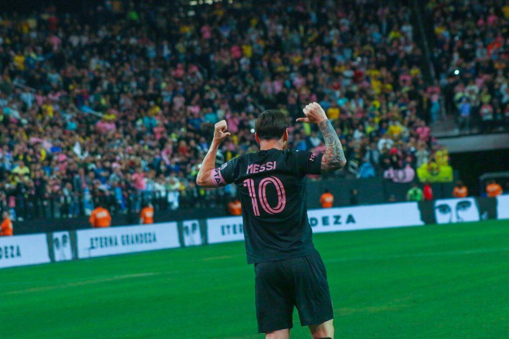 G⚽️ Lionel Messi celebrando en un partido de fútbol, vistiendo su camiseta número 10 durante un emocionante evento deportivo con espectadores en el estadio.