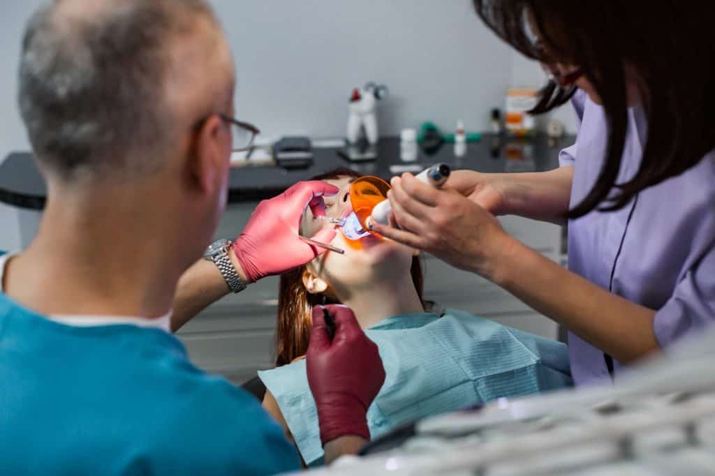 Clínica dental atendiendo a paciente durante tratamiento odontológico en consultorio profesional. – SoyMigrante.com REVISTA