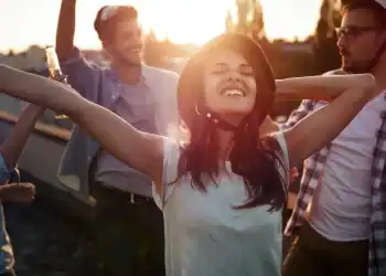 Jóvenes disfrutando de una fiesta al atardecer, celebrando la comunidad migrante y la integración cultural en un ambiente alegre y festivo. – SoyMigrante.com REVISTA