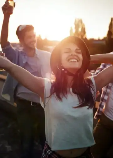 Relaciones humanas la clave para una vida feliz y saludable según Harvard3 – SoyMigrante.com REVISTA Jóvenes disfrutando de una fiesta al atardecer, celebrando la comunidad migrante y la integración cultural en un ambiente alegre y festivo.
