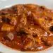 Jugos de carne guisada con salsa espesa y trozos de carne en plato blanco para recetas mexicanas o latinoamericanas.