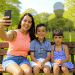 Mujer y dos niños tomando una selfie en un parque, promoviendo la inclusión social y la comunidad en la revista SoyMigrante.com REVISTA.