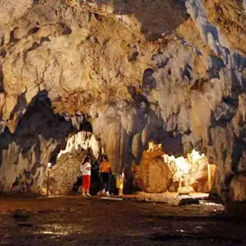 Cueva natural con visitantes explorando formaciones rocosas impresionantes y luz cálida en su interior, destacando turismo de aventura y cultura en espacios desconocidos.