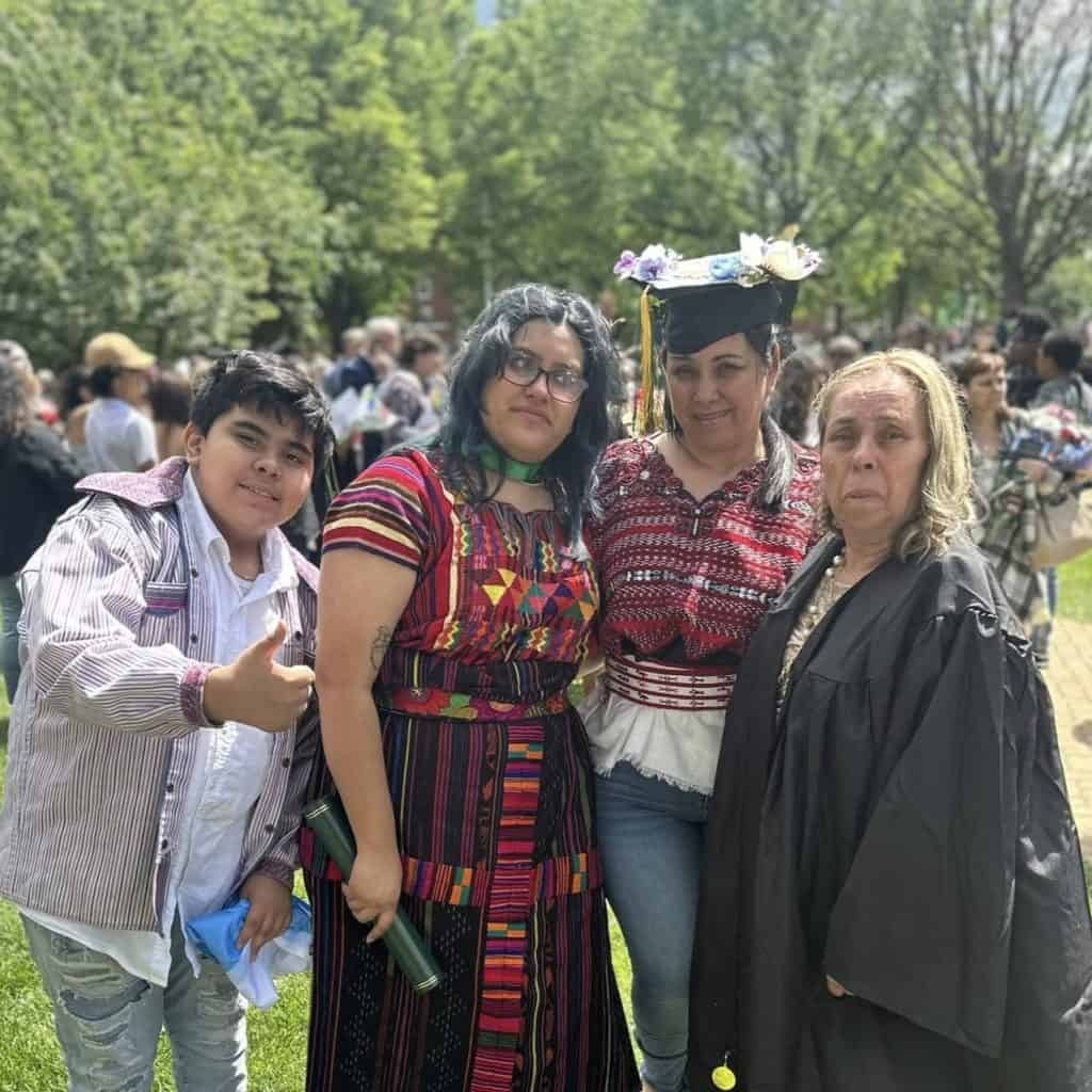 Diversas personas en celebración de graduation en un parque, mostrando orgullo y alegría, con árboles verdes y una multitud en el fondo, en un evento cultural y de reconocimiento académico. – SoyMigrante.com REVISTA