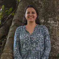 Paisaje con mujer sonriendo junto a árbol, naturaleza, vida saludable y bienestar, en entorno natural, moda casual, celebración de la diversidad, cultura y comunidad, mujer migrante, paisaje natural en verano.