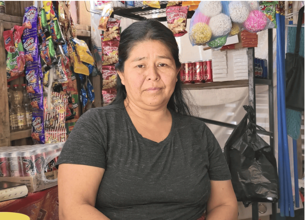 Seguridad laboral para migrantes, mujer en tienda de comestibles en mercado local, apoyo a justicia social, derechos laborales migrantes, comunidad inmigrante en México.