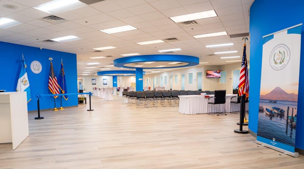 Amplia sala de conferencias con sillas, pantallas y bandera de Estados Unidos, preparada para eventos del Gobierno de El Salvador y temas migratorios en una infraestructura moderna.