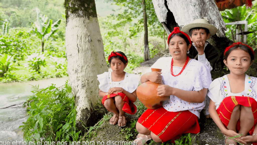 Niñas y mujer indígena en un entorno natural, símbolo de cultura, tradiciones y resistencia en comunidades rurales | Revive las historias y derechos de los migrantes en SoyMigrante.com REVISTA. – SoyMigrante.com REVISTA
