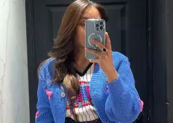 Soy-migrante-mujer-auténtica-vestido-colorido-vestimenta-tradicional, revistaporte, fotografía de una mujer con ropa tradicional mexicana, tomada en un espejo, reflejada en fondo oscuro.