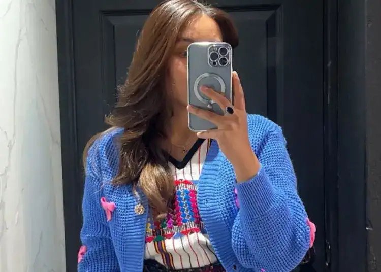 Soy-migrante-mujer-auténtica-vestido-colorido-vestimenta-tradicional, revistaporte, fotografía de una mujer con ropa tradicional mexicana, tomada en un espejo, reflejada en fondo oscuro.