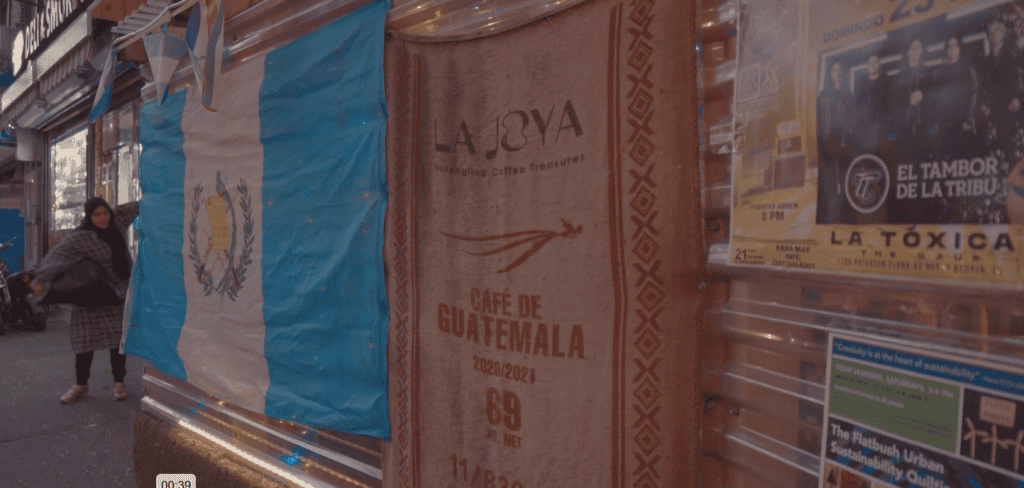 Guatemalan flag and coffee packaging display on a street in a migration-focused publication. – SoyMigrante.com REVISTA