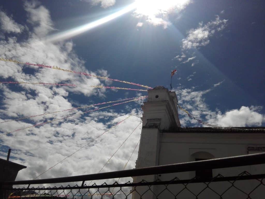 Cielo con nubes y banderines de celebración en una plaza, vista desde abajo, en un día soleado y despejado. – SoyMigrante.com REVISTA