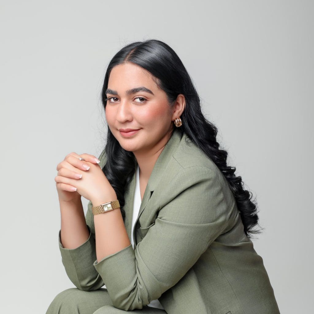 Profesional mujer inmigrante con estilo, cabello oscuro y blazer verde, reflejando liderazgo y confianza. Imagen adecuada para artículos sobre migración, derechos y experiencias de inmigrantes en la revista SoyMigrante.com REVISTA. – SoyMigrante.com REVISTA