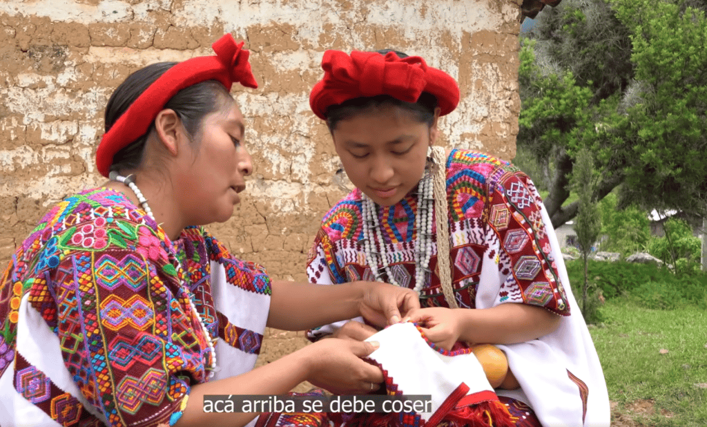 Tradición indígena y costura en comunidad originaria en México, mujeres artesanas con trajes tradicionales y bordados coloridos. – SoyMigrante.com REVISTA