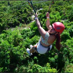 ¡Aventura en la naturaleza! Mujer practicando tirolesa en un entorno verde exuberante, disfrutando de actividades de turismo de aventura y naturaleza en un paisaje selvático.