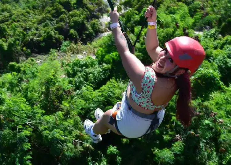 ¡Aventura en la naturaleza! Mujer practicando tirolesa en un entorno verde exuberante, disfrutando de actividades de turismo de aventura y naturaleza en un paisaje selvático.