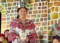 Vestido tradicional indígena con ornamentos y tocado de plumas, mujer en evento cultural de comunidad originaria en México, celebrando su identidad y patrimonio cultural.