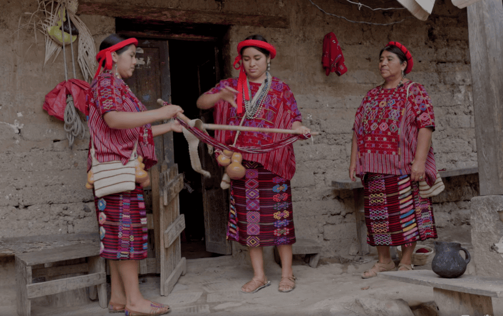Tradicionales mujeres mayas en Guatemala, vestidas con huipiles coloridos, participando en una ceremonia ancestral en el contexto de las historias de migrantes en SoyMigrante.com. – SoyMigrante.com REVISTA