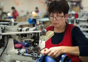 Trabajadora mexicana confeccionando en una fábrica, destacando la labor de las mujeres migrantes en el sector textil y de manufactura en México.