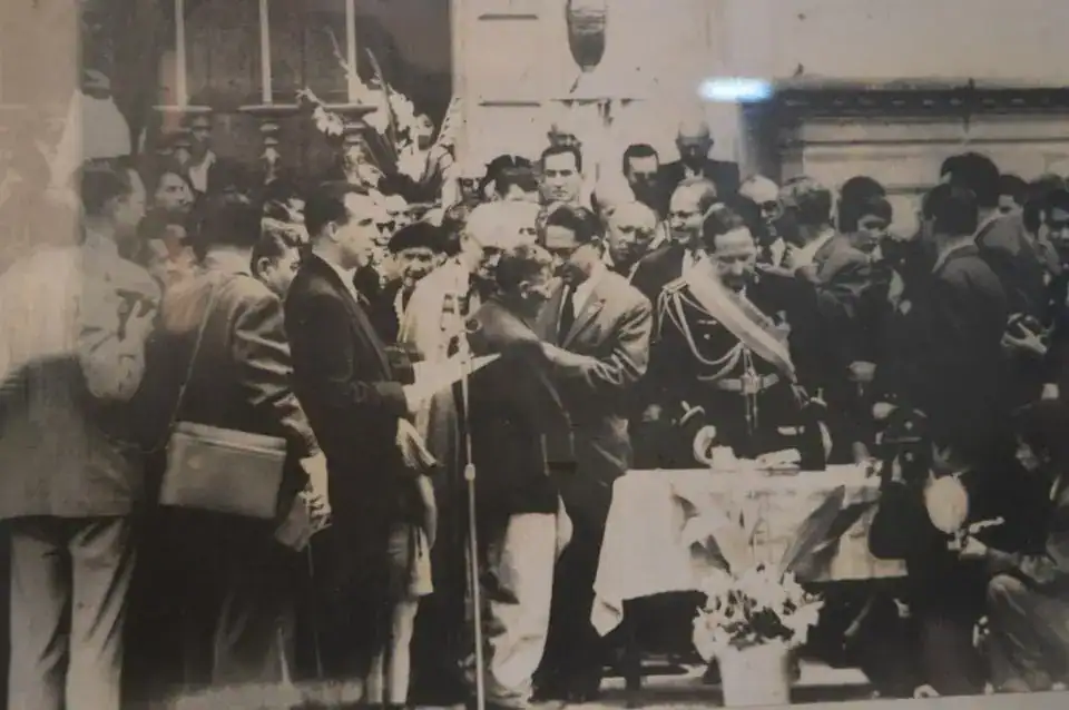 Hombres en una ceremonia o evento oficial en un entorno histórico, con varias personas vestidas formalmente y un acto que parece conmemorativo o diplomático. – SoyMigrante.com REVISTA