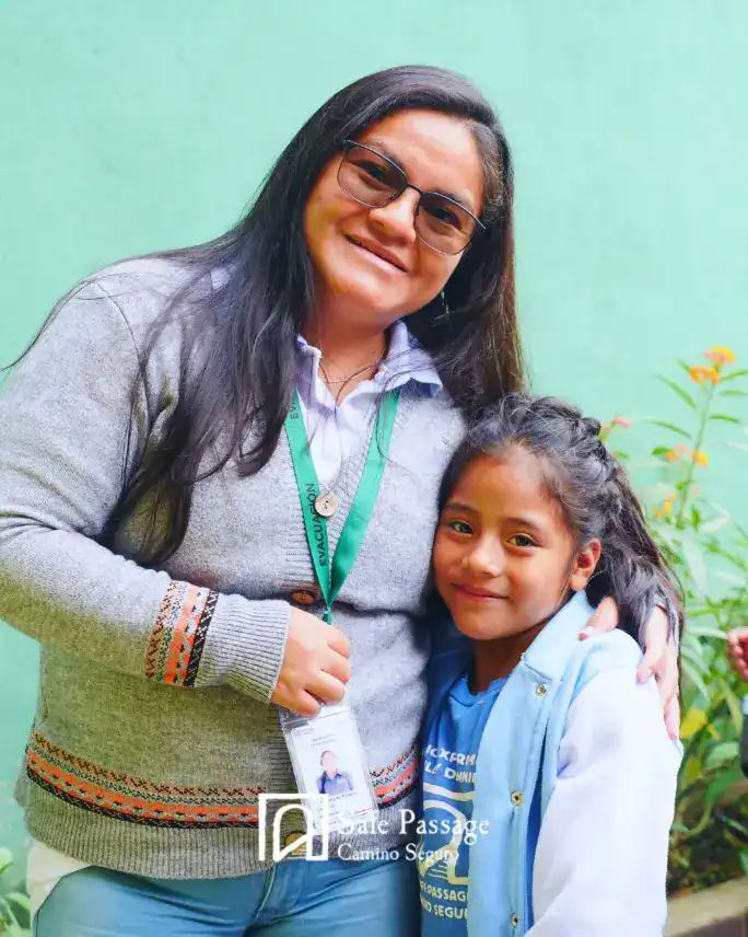 Personalizada por SoyMigrante.com REVISTA, fotográfica de una mujer migrante y niña sonriendo juntas en un entorno natural. – SoyMigrante.com REVISTA