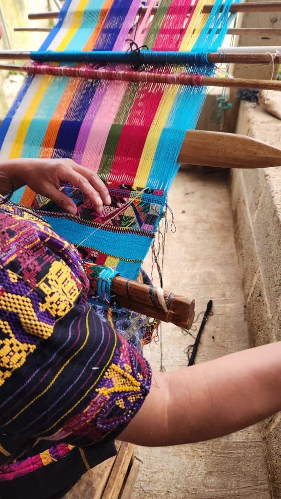 Colores vibrantes en tela tejida artesanalmente, mostrando el proceso tradicional de fabricación textil y el arte cultural en la artesanía indígena. – SoyMigrante.com REVISTA