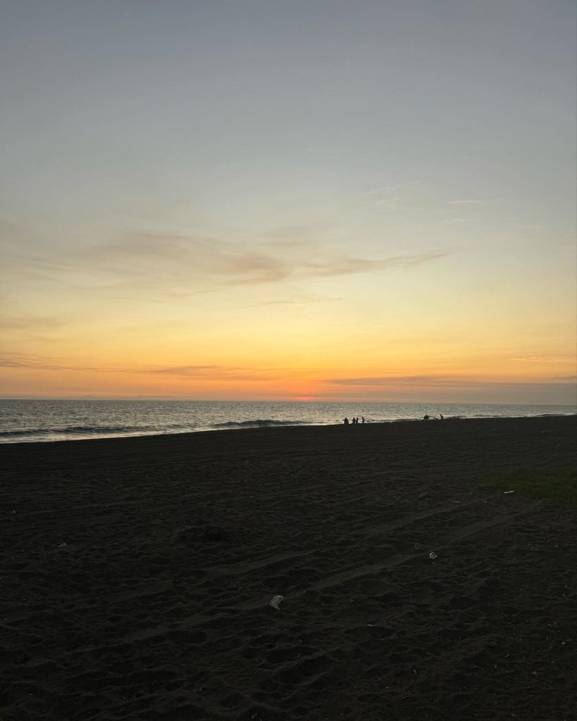 Atardecer en la playa con cielo colorido y olas suaves, ideal para reflexionar sobre migración y comunidad en un entorno natural y tranquilo. – SoyMigrante.com REVISTA