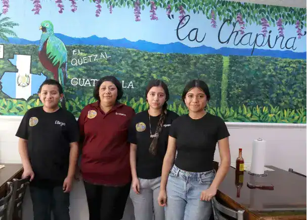 Quetzal de Guatemala y jóvenes en restaurante La Chaping, expresión de cultura y comunidad, en una imagen que refleja el trabajo y unión de migrantes en el contexto de SoyMigrante.com Revista.