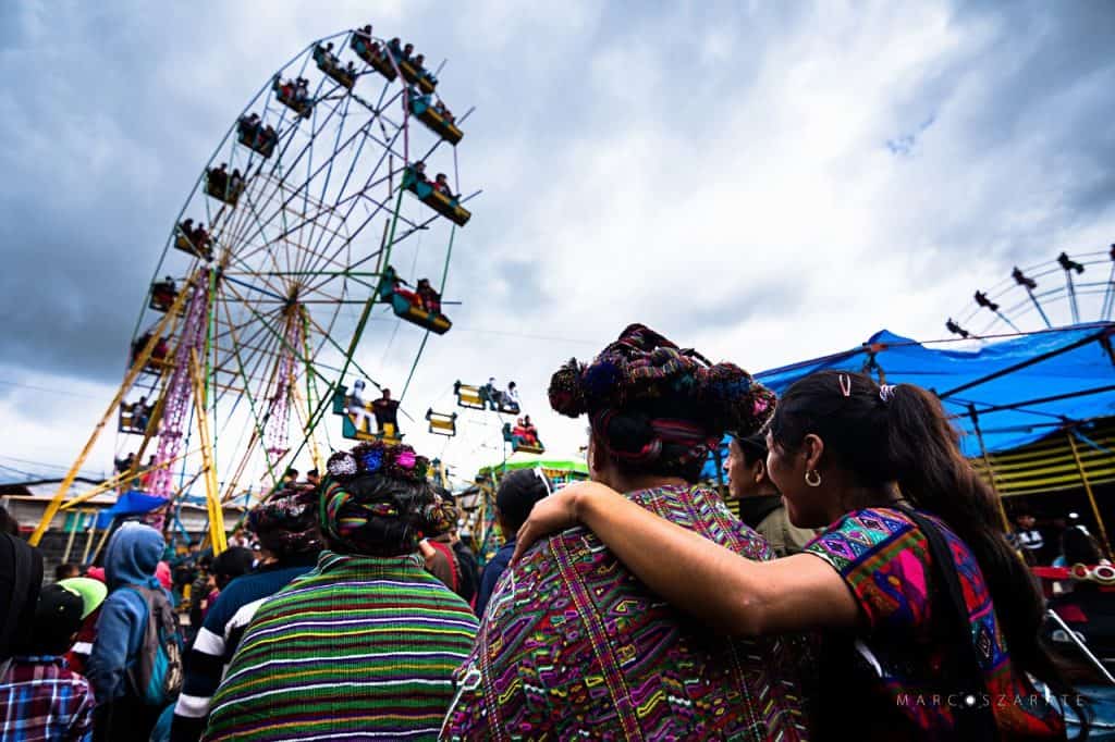 Vendedoras indígenas en feria tradicional, celebración cultural en Guatemala, ropa típica y ambiente festivo, en un día nublado, comunidad y tradición viva. – SoyMigrante.com REVISTA
