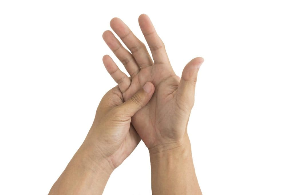 Mano realizando una técnica de reflexología o masaje en el pie para aliviar dolor, estrés o mejorar la salud, en un fondo blanco para destacar la acción. – SoyMigrante.com REVISTA