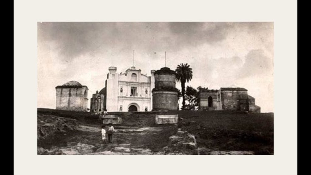 Arquitectura histórica de la iglesia en un estilo colonial en el centro de México, en tonos sepia, con un entorno rural y árboles, reflejando momentos pasados de la historia migrante. – SoyMigrante.com REVISTA