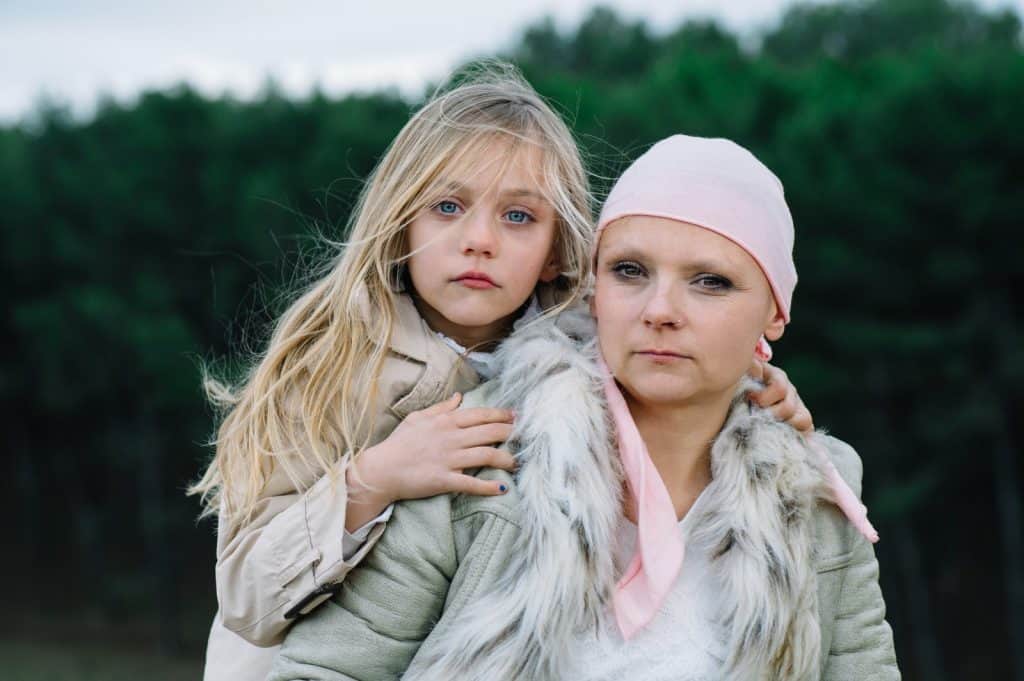 Niña y mujer con expresión seria en ambiente exterior, ambas con ropa de invierno y gestos pensativos, reflejando temas sociales y emocionales en la revista SoyMigrante.com Revista. – SoyMigrante.com REVISTA
