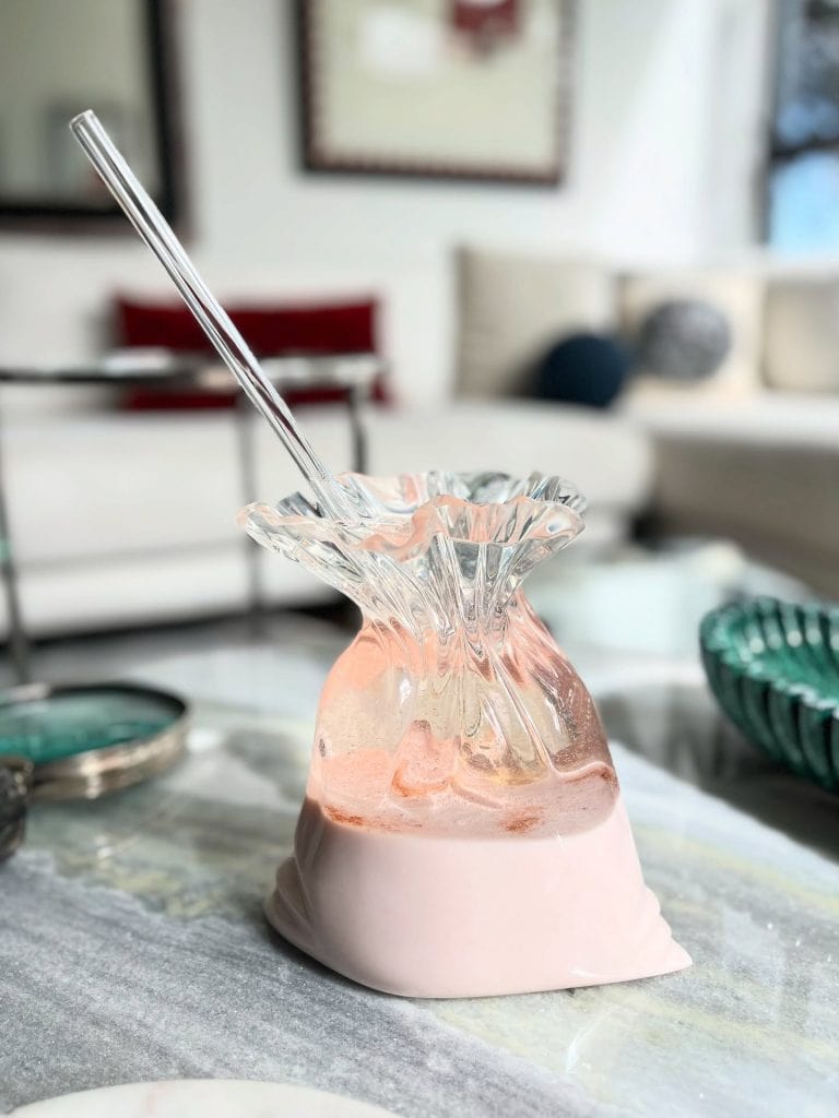 Jarrón de cristal con decoración en tonos rosados en un ambiente moderno y luminoso.