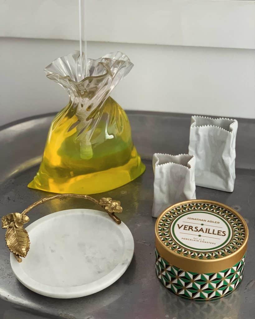 Vas decorativo de vidrio con aceite, sobres de azúcar y plato de mármol en estilo elegante y moderno. Ideal para revistas sobre estilo de vida, arte y diseño en la comunidad migrante.