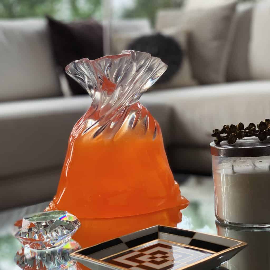 Jarrón de cristal con florero de vidrio en color anaranjado, decorativo y elegante, en un ambiente moderno y luminoso, ideal para la decoración del hogar o la oficina.