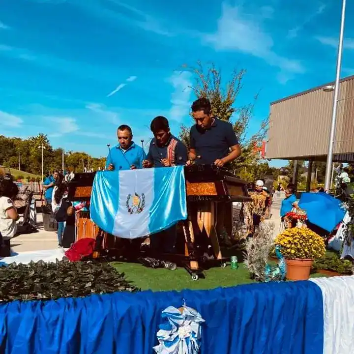 Suspenden dos actividades guatemaltecas en EE. UU. por solidaridad – SoyMigrante.com REVISTA Guatemaltegos en celebración con bandera y música en foro comunitario.